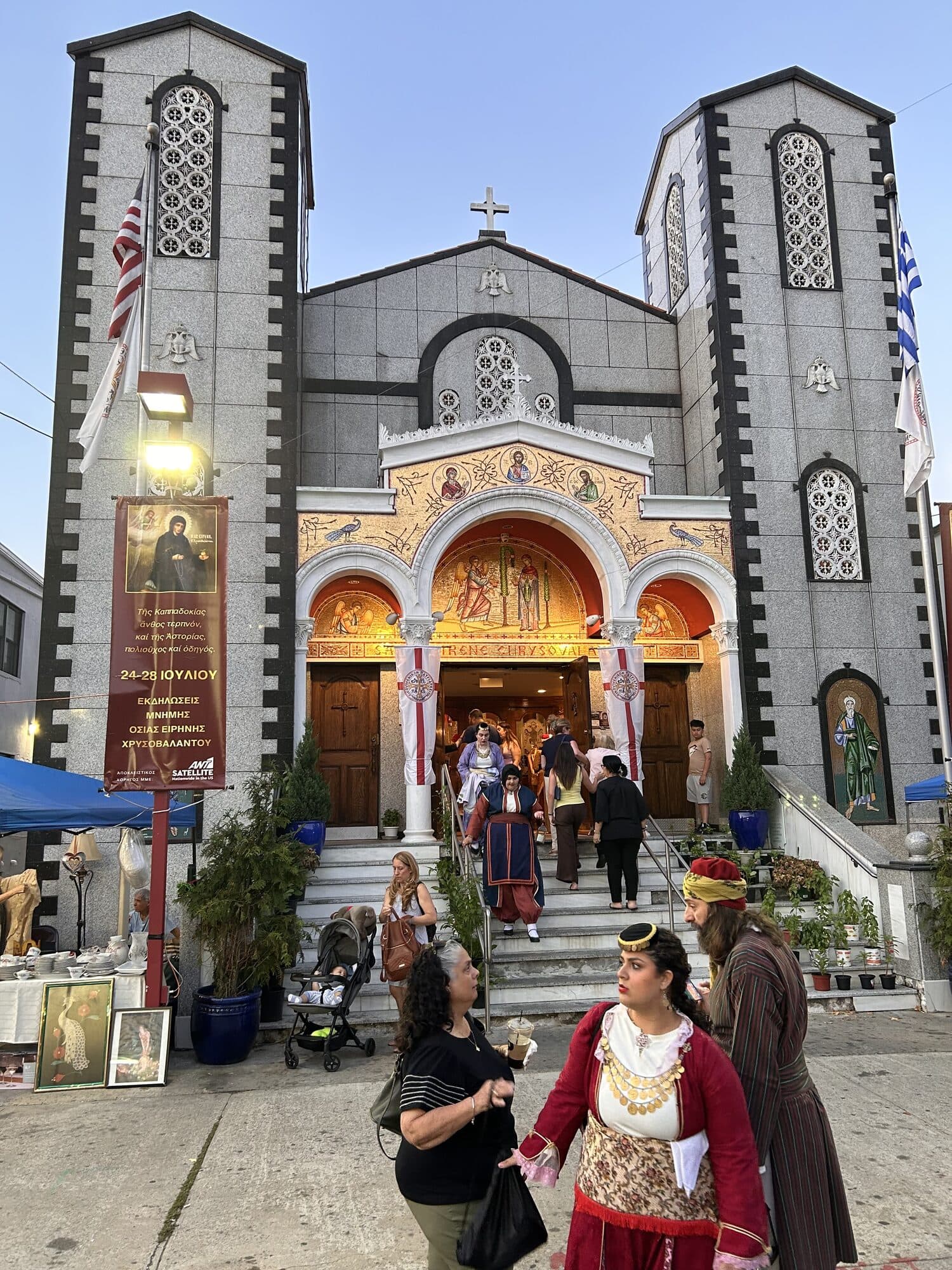 Worshippers on the front steps of St. Irene Chrysovalantou beneath the festival banner and American and Greek flags